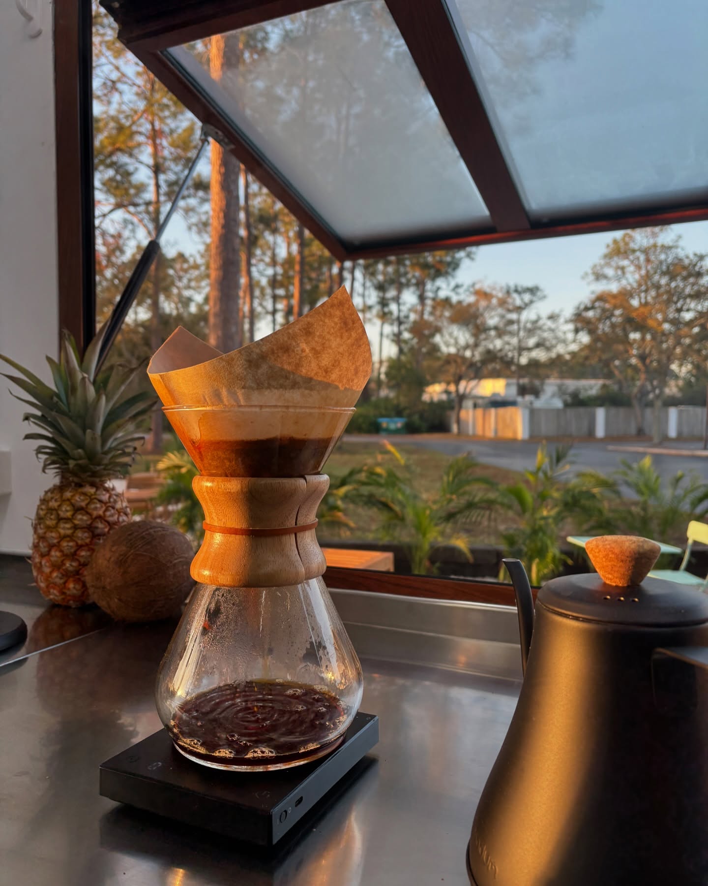 Pour-over coffee brewing beside a kettle at the open trailer window.